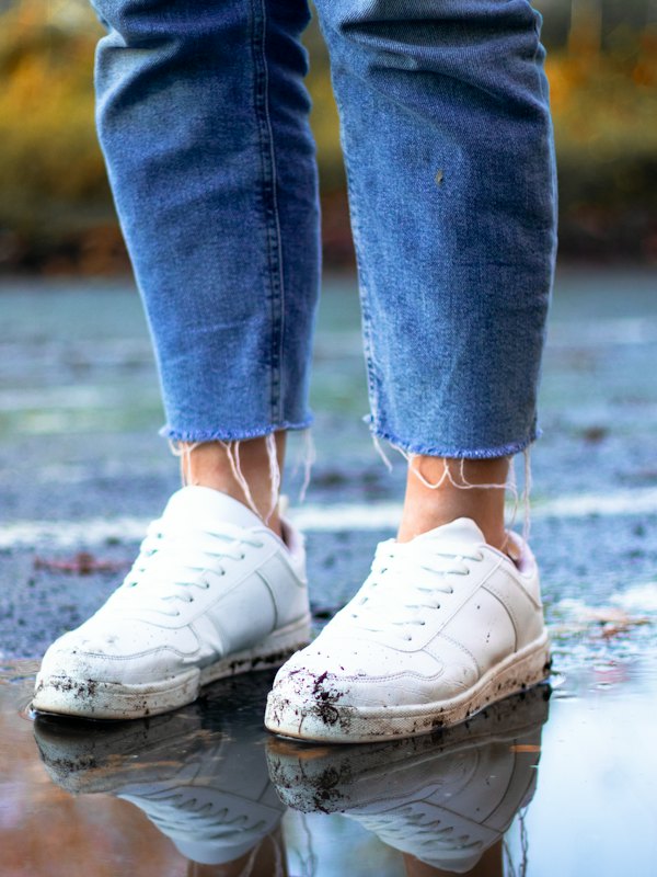White sneakers and cropped jeans on a wet street