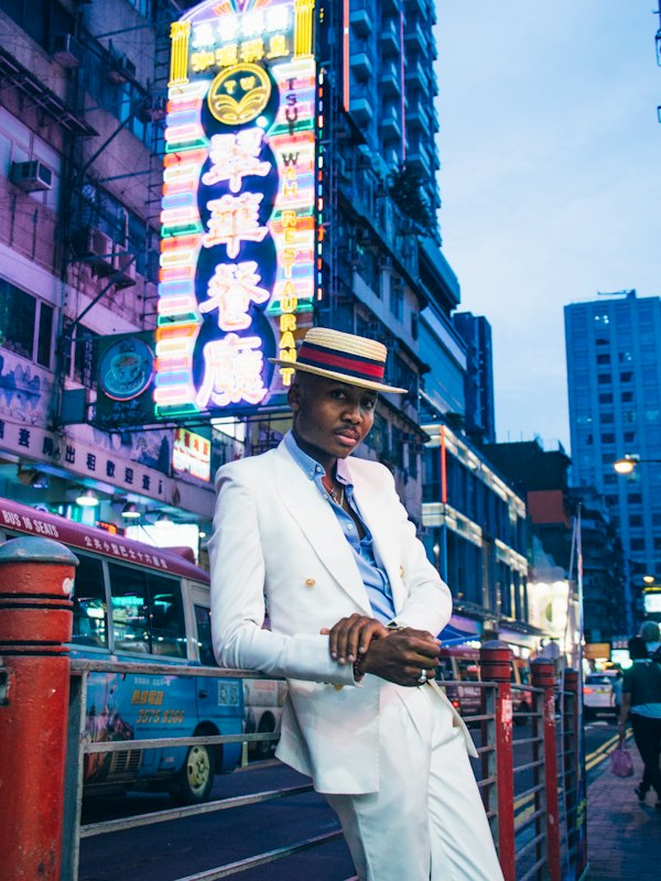 Man in a white suit on a neon-lit street